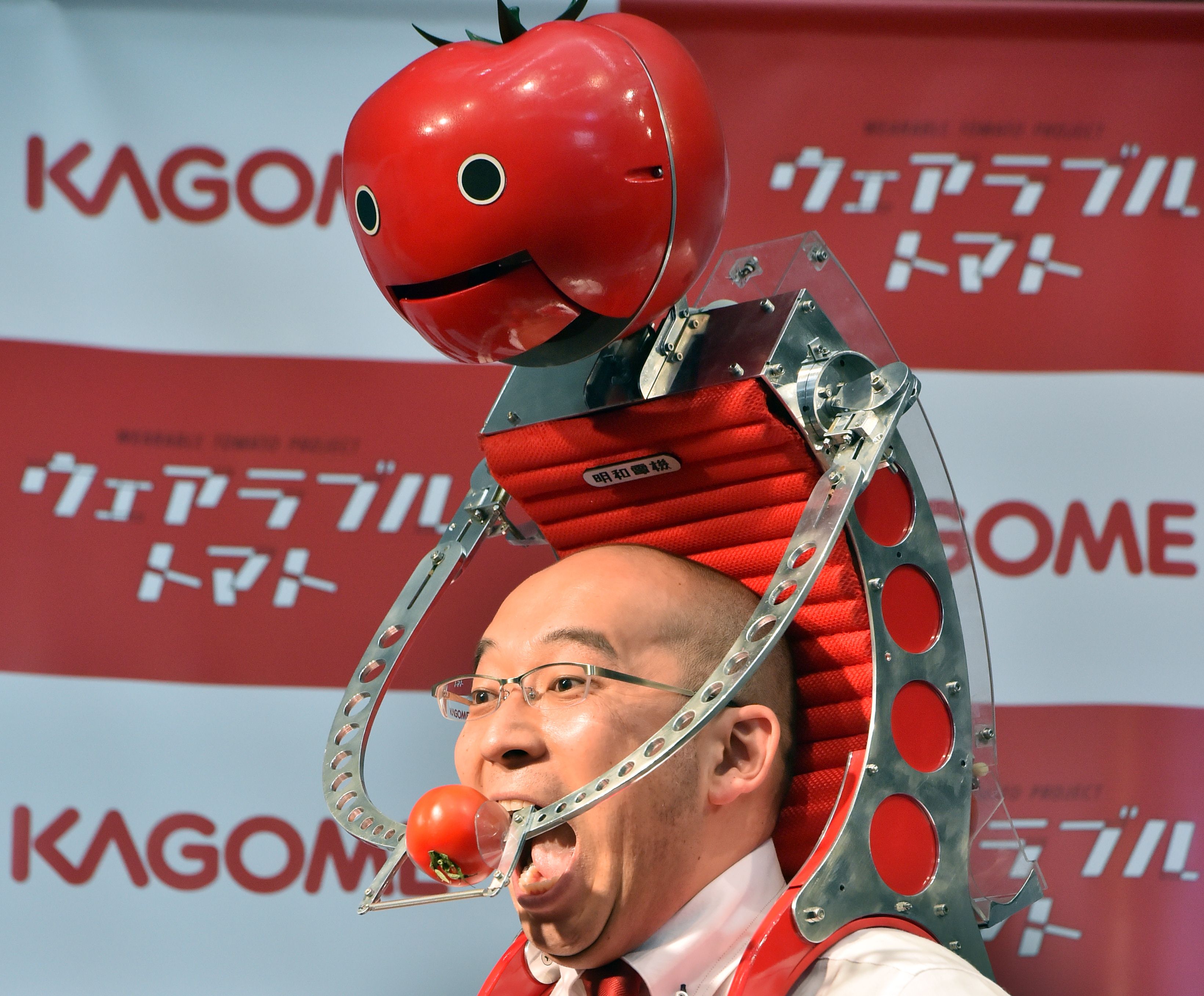Japan's food company Kagome employee Shigenori Suzuki tries to eat a tomato which is provided from the newly developed tomato dispenser for marathon runner 