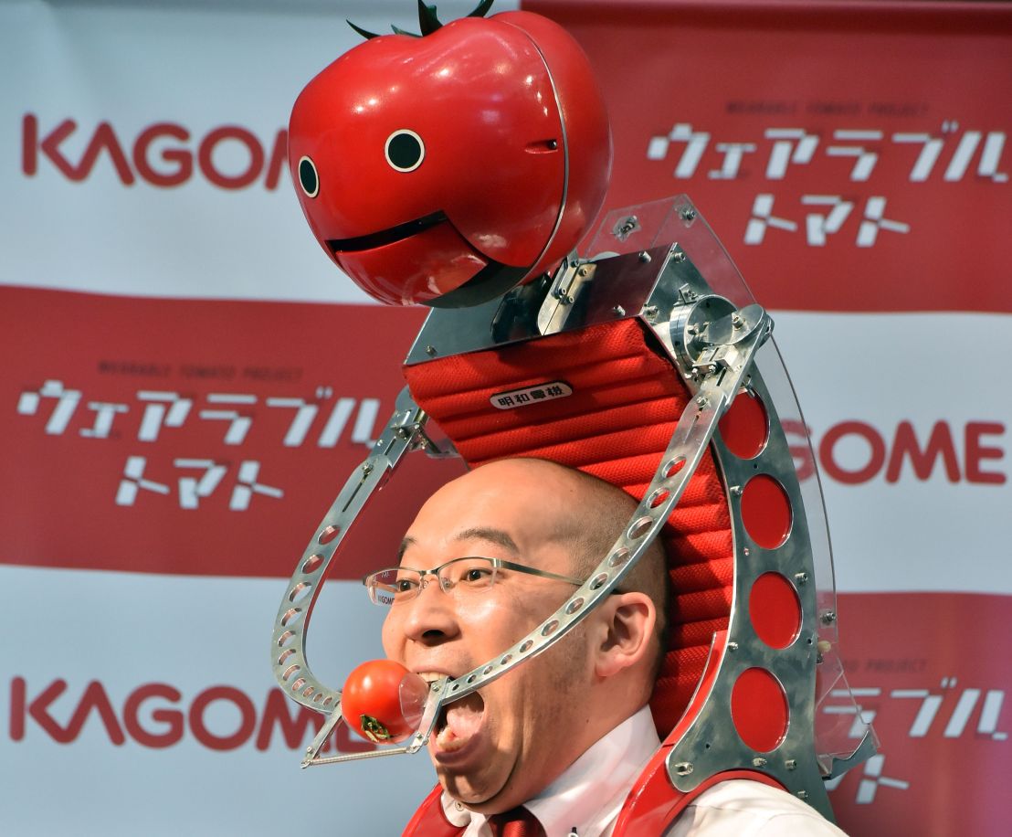 Japan's food company Kagome employee Shigenori Suzuki tries to eat a tomato which is provided from the newly developed tomato dispenser for marathon runner 