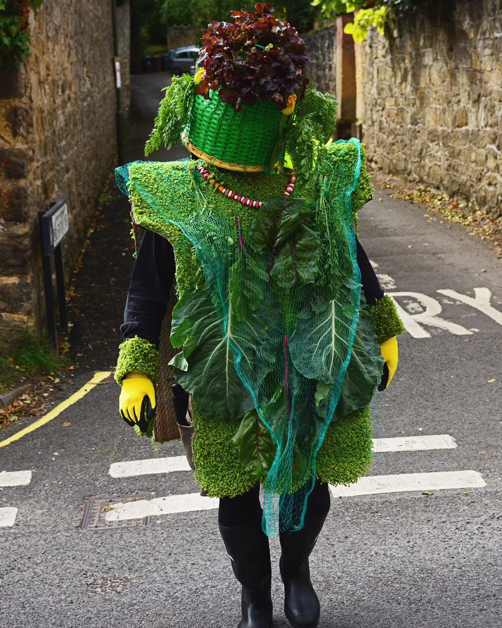 A green, full body costume made of wicker, greengrocer's artificial grass, and fresh plants and vegetables.