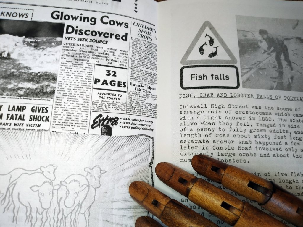 A wooden hand on a double page spread from a booklet, showing an old newspaper item and a report on falls of fish, crabs and lobsters.