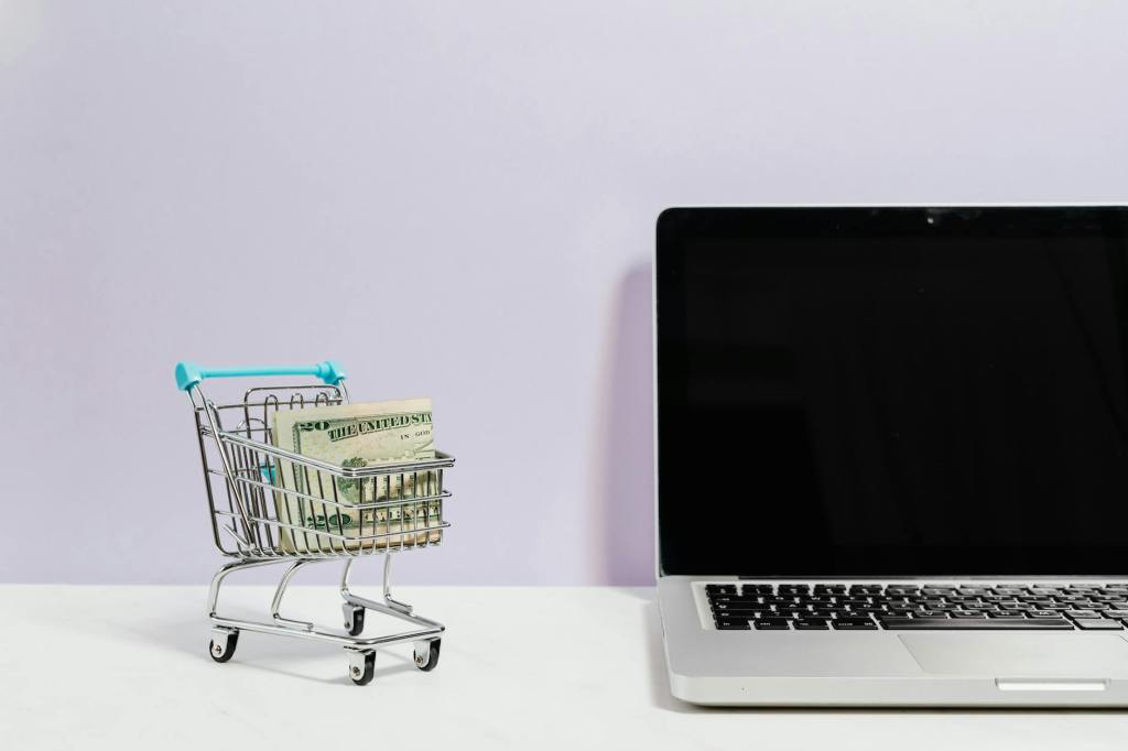 Some twenty dollar bills inside a tiny shopping trolley on a white desk, next to a Macbook Pro computer.