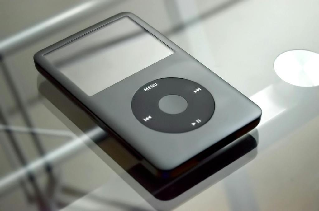 Closeup of a dark grey Apple iPod on a glass tabletop.